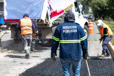 Puebla sokaklarında üç işçi yama yapıyor