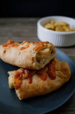 Altın kabuklu ve kremalı bir gurme pişirme, çarpıcı bir ışıklandırma ile koyu gıda tarzında sunulur. Kontrastlar ve dokular zarif bir ortamda gelişir.