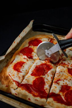  Erimiş peynirli gurme pepperoni pizza ve çıtır çıtır ekmek, ince ve zarif atmosferdeki zengin renk ve dokularını vurgulayarak koyu gıda tarzında sunuluyor.
