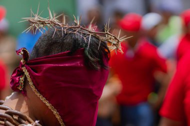Meksika, Atlixco 'daki Engrillados geleneği sırasında bir adamın kafasının yakın çekimi. Dikenli taç ve kırmızı kaplı yüz inancı, acıyı ve pişmanlığı simgeler..