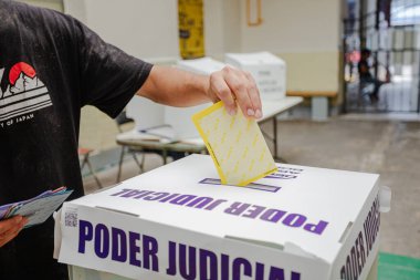 Bir el, Meksika 'da yapılan ilk adli seçimlerde Poder Yargı Komitesi etiketli saydam bir sandığa oy veriyor. Görüntü vatandaşların katılımını yakalıyor