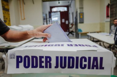 Bir el, Meksika 'da yapılan ilk adli seçimlerde Poder Yargı Komitesi etiketli saydam bir sandığa oy veriyor. Görüntü vatandaşların katılımını yakalıyor