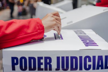 Bir el, Meksika 'da yapılan ilk adli seçimlerde Poder Yargı Komitesi etiketli saydam bir sandığa oy veriyor. Görüntü, vatandaşların tarihi bir oylamaya katılım ve seçim reformunu yansıtıyor 