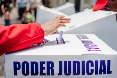 Bir el, Meksika 'da yapılan ilk adli seçimlerde Poder Yargı Komitesi etiketli saydam bir sandığa oy veriyor. Görüntü, vatandaşların tarihi bir oylamaya katılım ve seçim reformunu yansıtıyor 