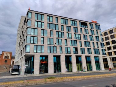 Berlin, Almanya - 6 Temmuz 2022: Gri cepheli ve işlek yolda duran birçok küçük pencereli yeni inşa edilmiş modern otel.