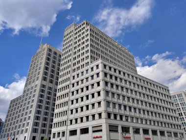 Berlin, Almanya - 4 Temmuz 2022: Beyaz cepheli ve arka planda bulutlu gökyüzü olan küçük pencereli büyük idari bina.