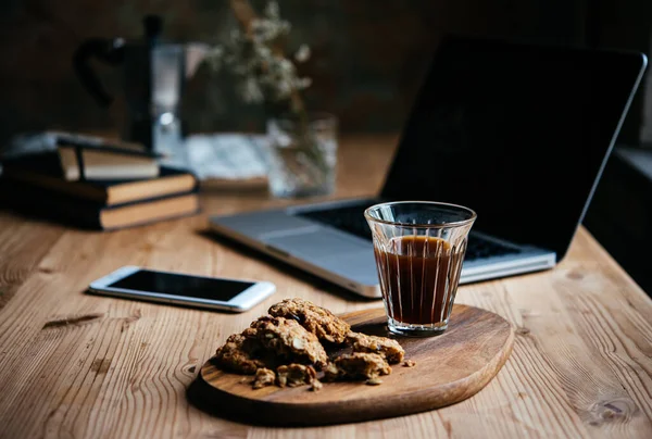 咖啡和一些小吃在与笔记本电脑和书籍为背景休息的时候提供 在家工作的概念 — 图库照片