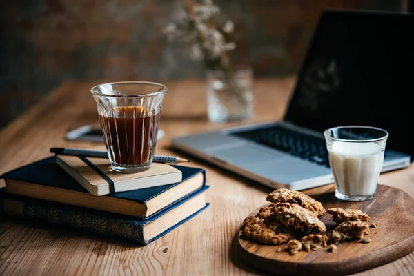 咖啡和一些小吃在与笔记本电脑和书籍为背景休息的时候提供 在家工作的概念 — 图库照片