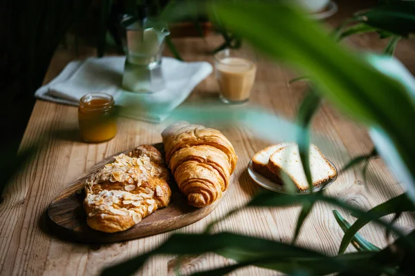 与羊角面包和咖啡共进早餐 餐桌上满是美丽的植物 享受家庭生活的乐趣 — 图库照片