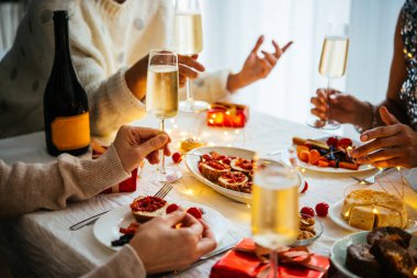 Arkadaşlar Noel ya da yılbaşı partisinde şampanya ya da köpüklü şarapla kutlama masasında sohbet ediyorlar.