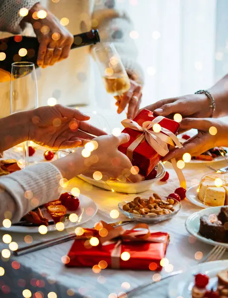 Friends hand in gifts at a party table celebrating Christmas or New Year