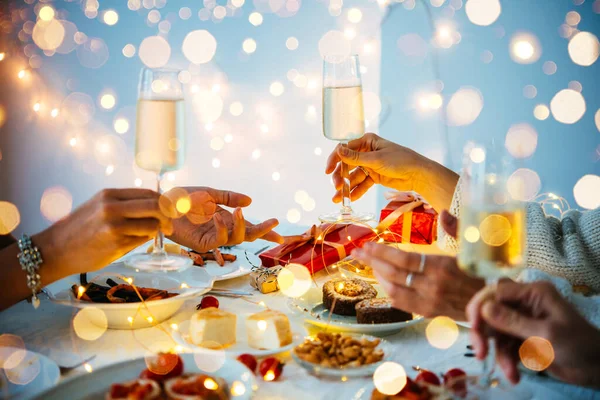 Friends enjoying conversation at a celebration table for Christmas or New Year\'s Eve party with sparkling wine or champagne