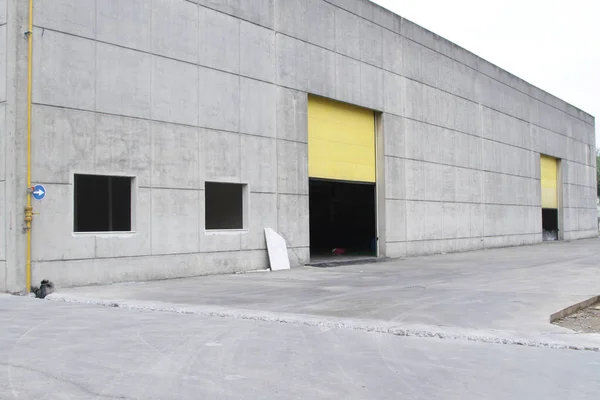 Warehouse building with yellow sectional door, window and gray wall.