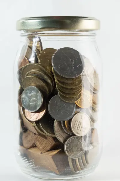 Many coins in transparent jar, change, isolated white background