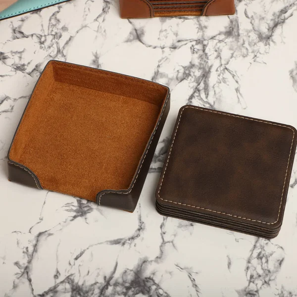 Leather table mats in different colors. Concept shot, top view. Custom background view of leather table coaster. Stitched and leather table coaster.
