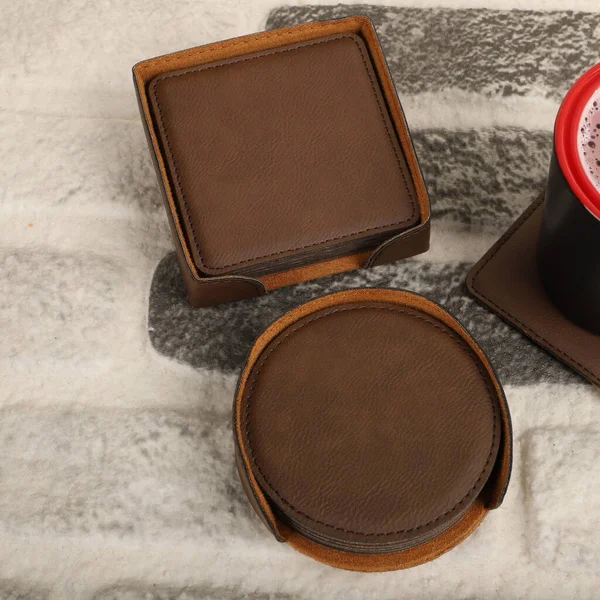 Leather table mats in different colors. Concept shot, top view. Custom background view of leather table coaster. Stitched and leather table coaster. Beverage coaster.