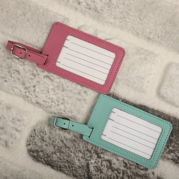 Leather luggage tags in teal and pink colors. Concept shot, top view. Custom background, luggage tags view. Empty Travel Luggage Label, Space blank for text.
