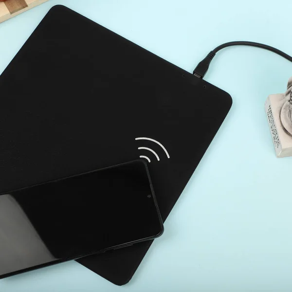 Charging the smartphone with leather wireless charger on desk. Colorful leather charger pads. Wireless mousepad, Charger pad. Closeup, top view, no people. Concept shoot.