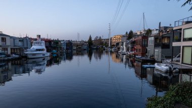 Günbatımında ünlü yüzen ev halkı, renkli yüzen yüzen yüzen yüzen yüzen tekneler, demirli tekneler ve durgun suya sakin yansımalar sunuyor. Yumuşak akşam ışığı ve mimari cazibesi bu görüntüyü seyahat, yaşam tarzı ve gayrimenkul için ideal kılıyor.. 