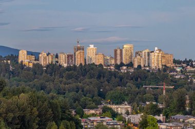 Vancouver Şehir Merkezi Skyline ile Endüstriyel Rıhtım, Gökdelenler Burrard Körfezi 'nde Akşam Işığında Yansıdı. Günbatımında parlayan gökdelenler, sanayi kıyısı ve Stanley Parkı 'nın kıyı kenti manzarasına kontrastlık ve derinlik katmasıyla.
