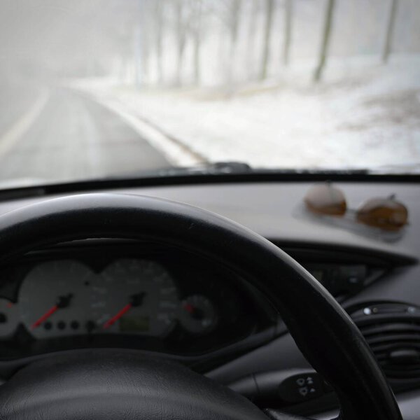 Dangerous winter season with snow on the road. The interior of the car from the driver's point of view - dangerous traffic in bad weather.