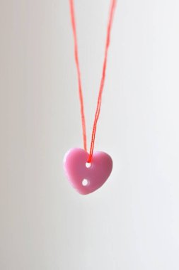 Beyaz arka planda iplik olan kırmızı kalp şeklinde bir iğne. Sevgililer Günü, aşk konsepti.