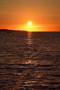 Deniz ve dalgalarla kumsalda güzel renkli bir gün batımı. Seyahat, tatil ve deniz kenarında yaz tatili konsepti. Yunanistan - Korfu Adası - Agios Georgios