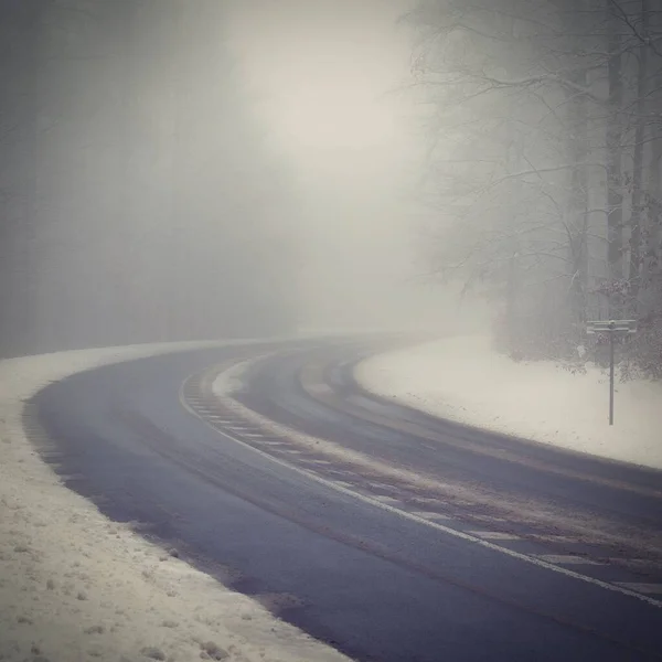 Bad weather driving - foggy hazy country road. Motorway - road traffic. Winter time. Autumn - fall.  Snow and frost on the road in winter.
