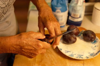 Yaşlı eller bıçakla turta yapıyor.