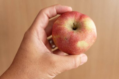 Elinde kırmızı bir elma tutarken
