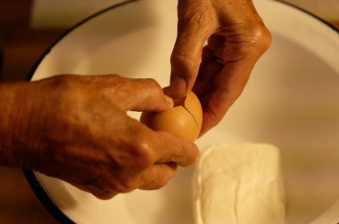 Eski bir tabak ekmek ve un rulolarını ahşap masaya koyan bir kadının ellerini kapatın.