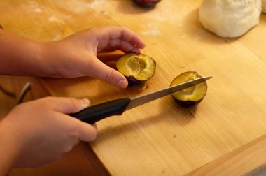 Çocuk hamuru bıçakla kesiyor.