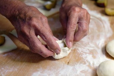 Kadın elleri tahta tahtada un yoğuruyor, merdaneyle. Ev yapımı hamur köftesi pişirmek. Ev yapımı yemek..
