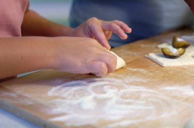 Çocuk elleri merdane ve undan hamur yapıyor.