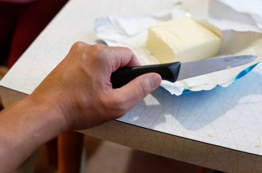 Bıçak, tahtanın üzerinde siyah bıçakla beyaz peynir parçalarına ayrılmış. Bıçak ve masa üzerinde bıçak.