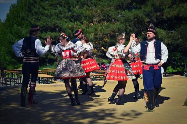 Brno - Bystrc, Czech Republic, 22 June, 2024. Traditional festivities of the feast of the feast in the Czech Republic. Food and drink festival. Girls and boys dancing in beautiful colourful costumes. clipart