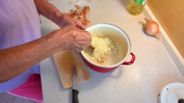 Mutfakta yemek yapan yaşlı bir kadın.