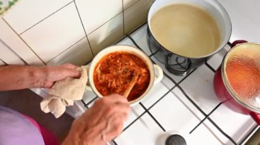 Adam domates sosu pişiriyor.