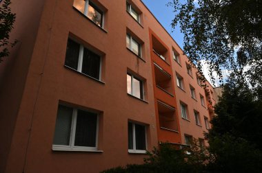 Pencereleri ve balkonları olan modern bir apartmanın ön cephesi. 