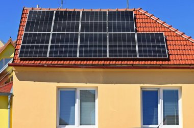 Çatıda güneş panelleri olan bir aile evi. Ev fotovoltaik enerji santrali. Endüstri kavramı ve yenilenebilir kaynaklardan daha ucuz yeşil elektrik.