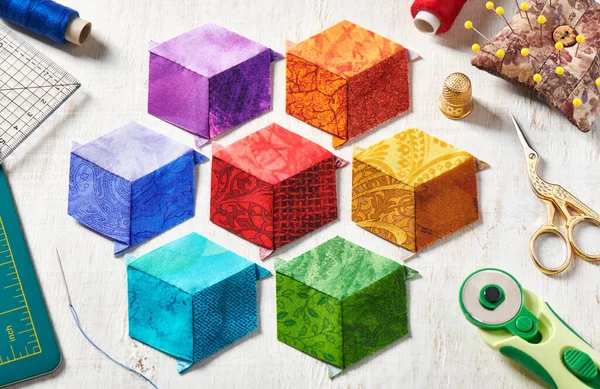 Diamonds stitched in the form of a cubes in the colors of the rainbow, quilting and sewing accessories.