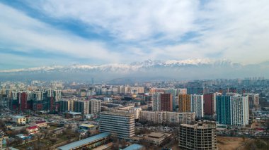 Almaty, Kazakistan - 11 Mart 2022: Yeni yüksek binaları olan kentsel alan. Dağların arka planında ve bulutlu gökyüzünde.