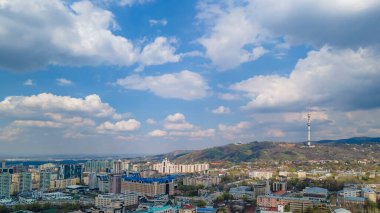 Almaty, Kazakistan - 12 Nisan 2022: şehrin çok katlı binaları ve dağda bir TV kulesi. Drone bakış açısı