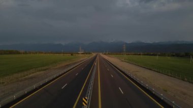 Trafiksiz dört şeritli otoyol. Bulutlu. Arka planda dağlar
