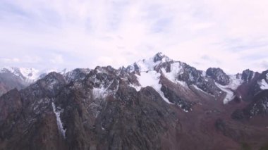 Karda büyük kayalık tepeler. Hava bulutlu. Dağlık arazi