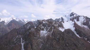 Dağlık yamaçlardaki karlı kayalıklara uçmak. Bulutlu hava