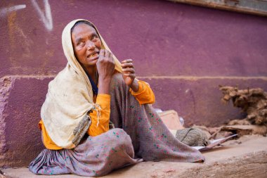 GOA, Hindistan - 22 Şubat 2024: Zavallı kadın kirli zeminde oturuyor.