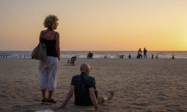 GOA, Hindistan - 23 Şubat 2024: Yetişkin çift gün batımında plajda dinleniyor. Seyahat süresi