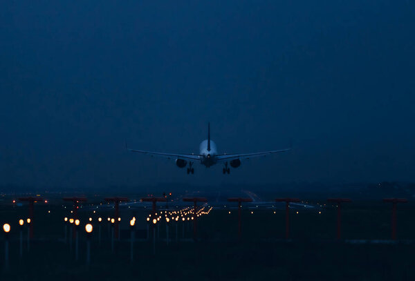 An airplane flies over the runway for landing. Evening time