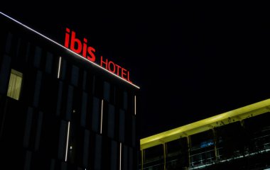 Almaty, Kazakistan - 18 Ocak 2025: Binanın ön cephesindeki Ibis otelinin adı. Gece vakti. Uluslararası ağ                            